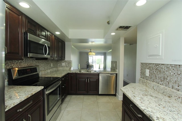 kitchen featuring light tile patterned flooring, sink, hanging light fixtures, a raised ceiling, and stainless steel appliances