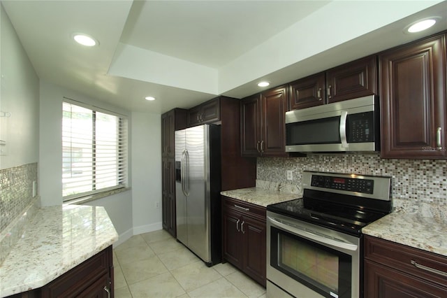 kitchen with light stone counters, appliances with stainless steel finishes, light tile patterned floors, and backsplash