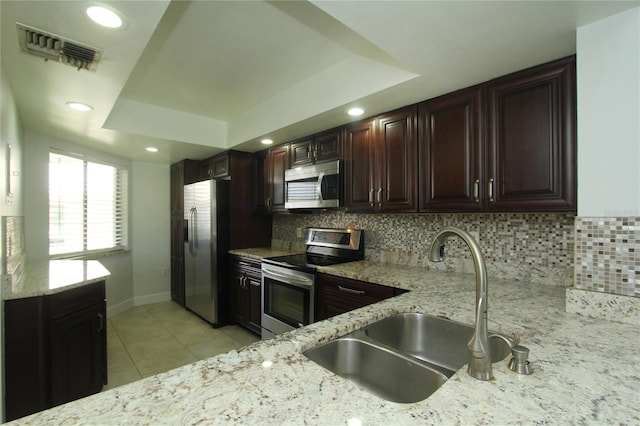 kitchen with tasteful backsplash, appliances with stainless steel finishes, a tray ceiling, and sink