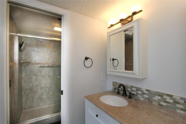 bathroom featuring vanity, an enclosed shower, backsplash, and a textured ceiling