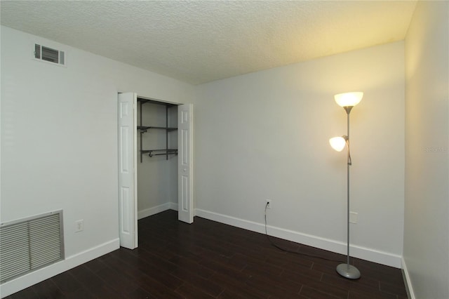 unfurnished bedroom with dark wood-type flooring, a closet, and a textured ceiling