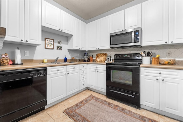 kitchen with light tile patterned flooring, sink, white cabinets, decorative backsplash, and black appliances