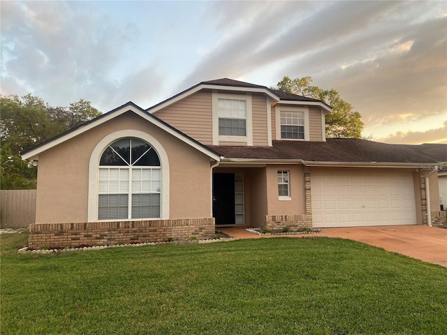 traditional-style home featuring stucco siding, a front lawn, concrete driveway, a garage, and brick siding