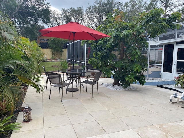 view of patio with outdoor dining space, a sunroom, and fence