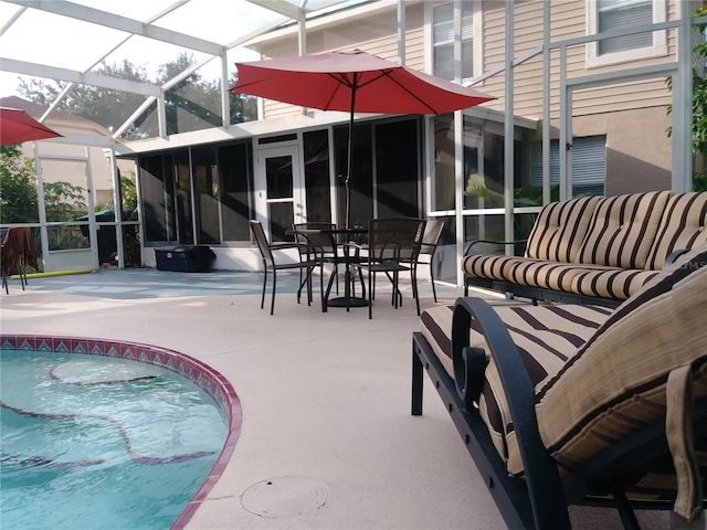 view of pool with glass enclosure, a patio, and a sunroom