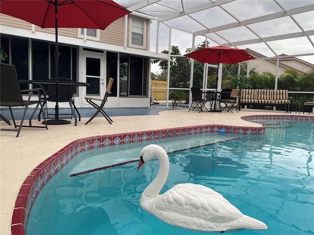 view of swimming pool featuring glass enclosure, a patio, and a fenced in pool