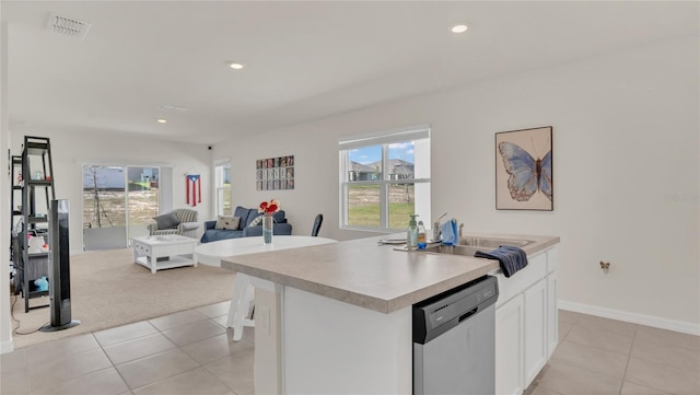 kitchen with a center island with sink, white cabinetry, stainless steel dishwasher, and light tile patterned flooring