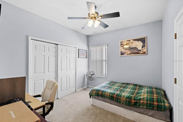 bedroom with ceiling fan, a closet, light carpet, and a textured ceiling