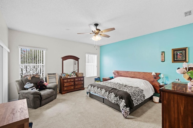 carpeted bedroom featuring ceiling fan and a textured ceiling