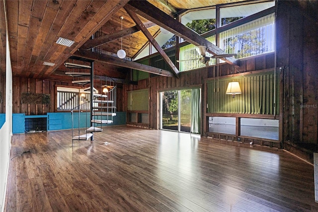 unfurnished living room featuring hardwood / wood-style floors, beam ceiling, wooden walls, high vaulted ceiling, and wooden ceiling