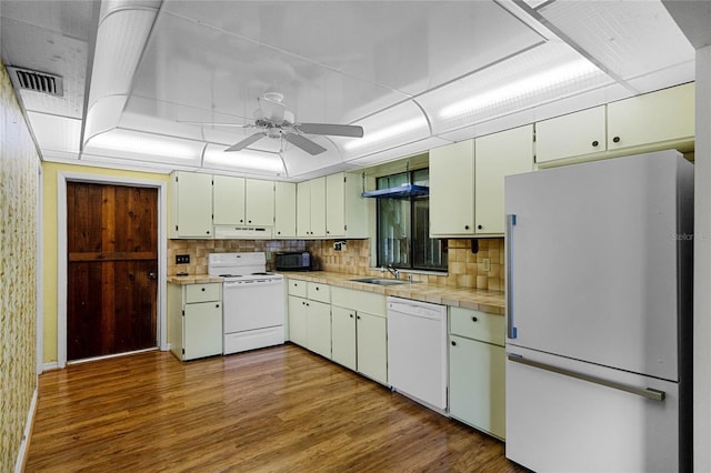 kitchen featuring sink, white appliances, backsplash, a raised ceiling, and light wood-type flooring