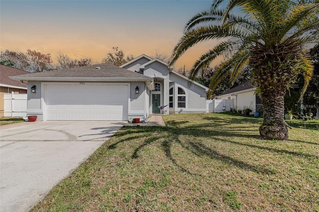 view of front of property with fence, driveway, a front lawn, and stucco siding