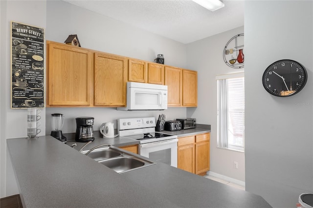 kitchen with white appliances, light brown cabinetry, sink, and a textured ceiling