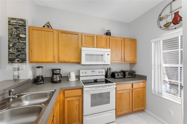 kitchen featuring sink, light tile patterned floors, and white appliances