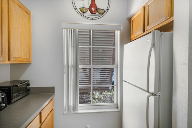 kitchen featuring light brown cabinetry and white refrigerator