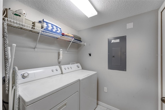 laundry area with electric panel, washer and dryer, and a textured ceiling