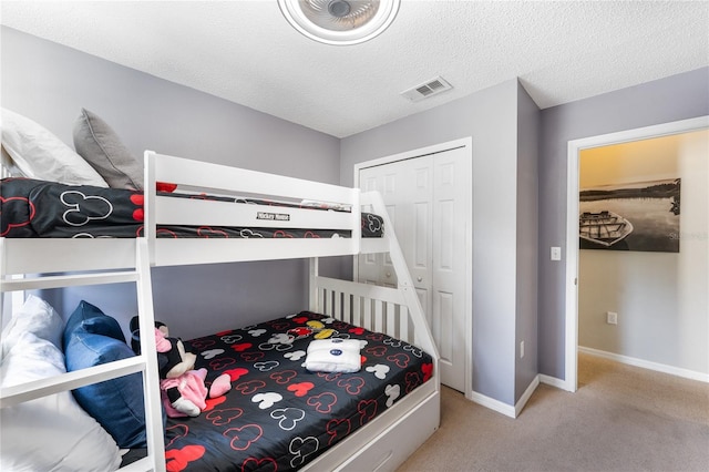 carpeted bedroom with a textured ceiling and a closet