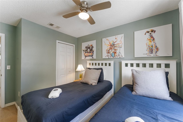 carpeted bedroom with a textured ceiling, ceiling fan, and a closet