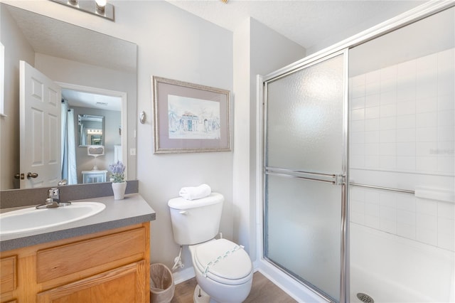 bathroom featuring vanity, toilet, a shower with door, and a textured ceiling