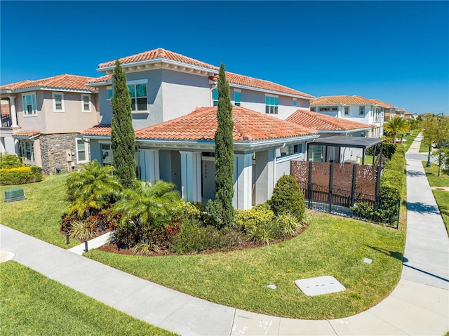 view of front facade with a residential view, a tiled roof, a front yard, and fence