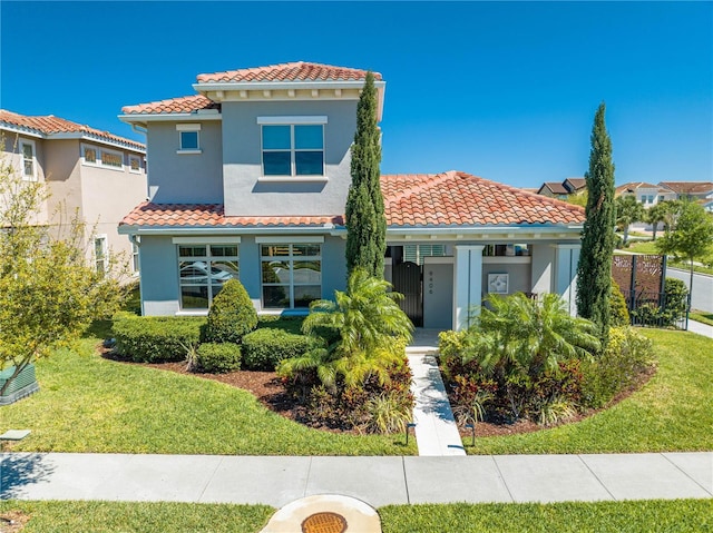 mediterranean / spanish-style home featuring a tile roof, a front yard, and stucco siding