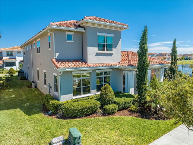 rear view of house featuring a yard, central AC, stucco siding, and a tile roof