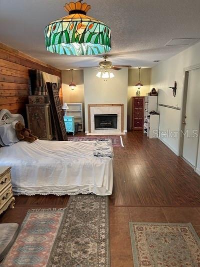bedroom with wood-type flooring, wooden walls, and a textured ceiling
