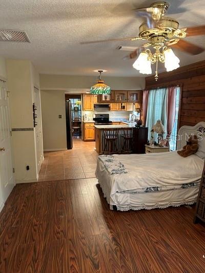 bedroom with hardwood / wood-style flooring, stainless steel fridge, and a textured ceiling