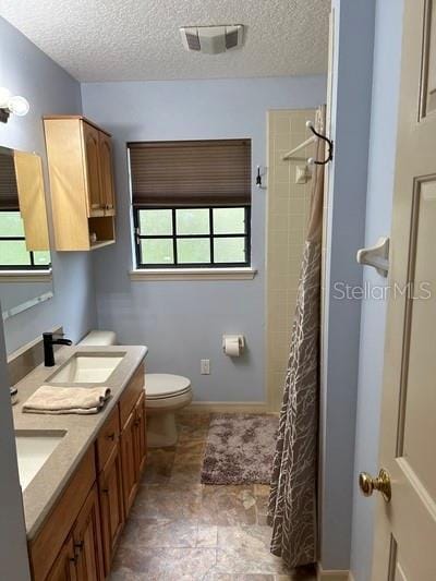 bathroom with a shower with curtain, vanity, toilet, and a wealth of natural light