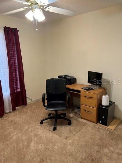 carpeted home office featuring ceiling fan
