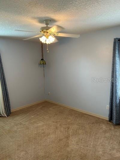 unfurnished room with ceiling fan, carpet flooring, and a textured ceiling