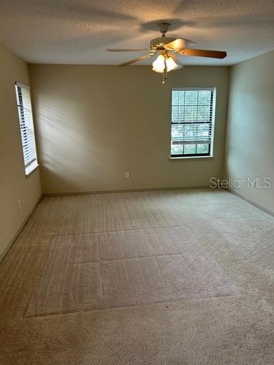 carpeted spare room with ceiling fan and a textured ceiling