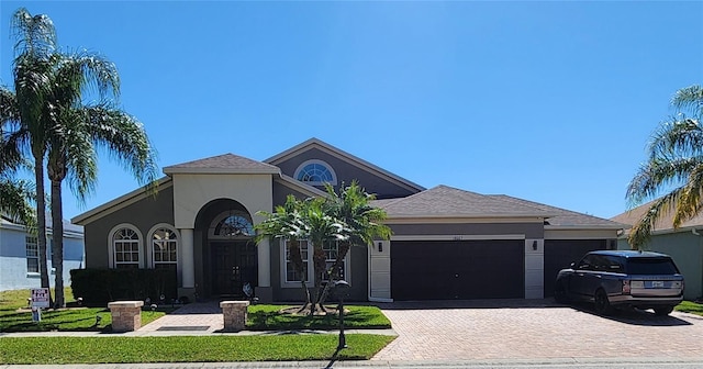 view of front of house with stucco siding, decorative driveway, and a garage