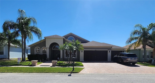 view of front of property featuring stucco siding, an attached garage, and decorative driveway