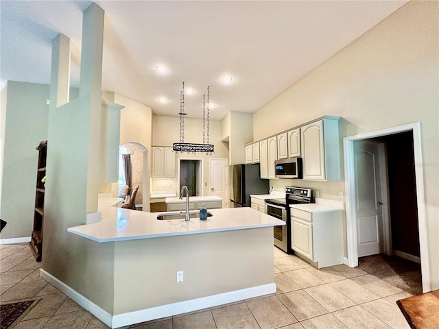 kitchen with white cabinetry, sink, light tile patterned floors, kitchen peninsula, and stainless steel appliances