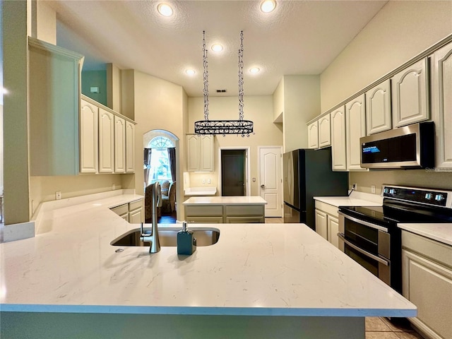 kitchen featuring sink, a center island, hanging light fixtures, a textured ceiling, and stainless steel appliances