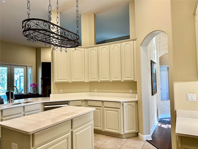 kitchen featuring decorative light fixtures, sink, stainless steel dishwasher, light tile patterned floors, and french doors