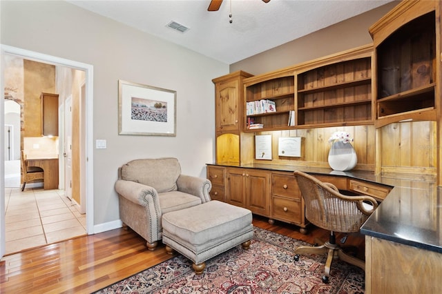 office area with hardwood / wood-style flooring, built in desk, and ceiling fan