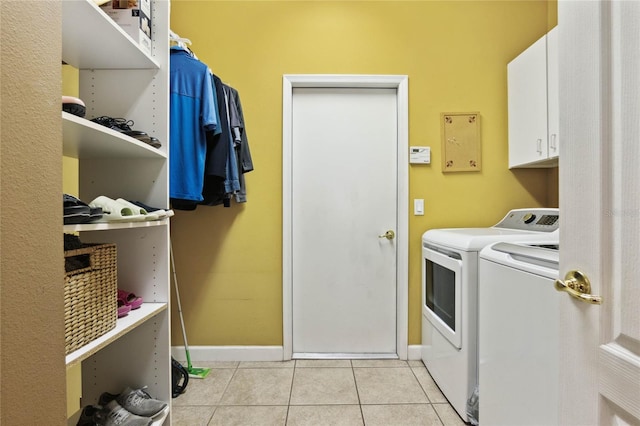 laundry area with cabinets, light tile patterned flooring, and washing machine and clothes dryer