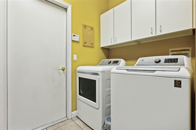 laundry room with cabinets, washing machine and dryer, and light tile patterned floors