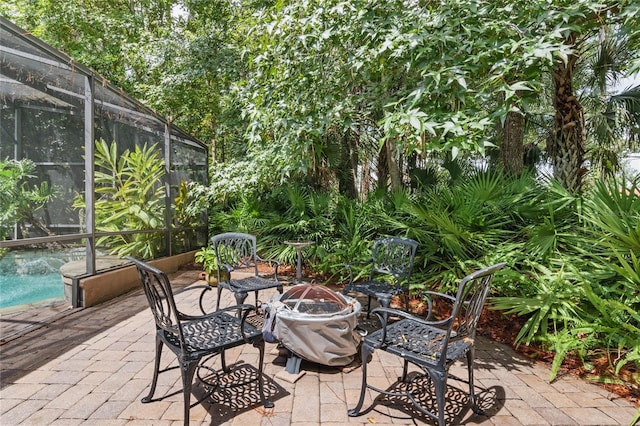 view of patio / terrace featuring a fire pit and glass enclosure