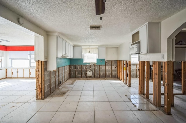 kitchen featuring white cabinetry, ceiling fan, a healthy amount of sunlight, and light tile patterned floors