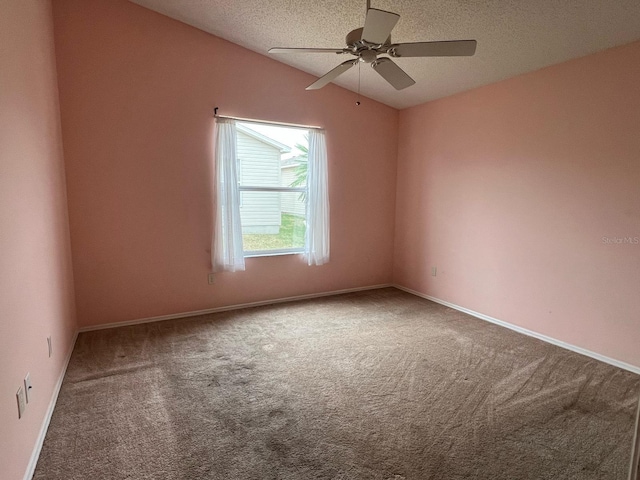 carpeted empty room featuring ceiling fan, vaulted ceiling, and a textured ceiling