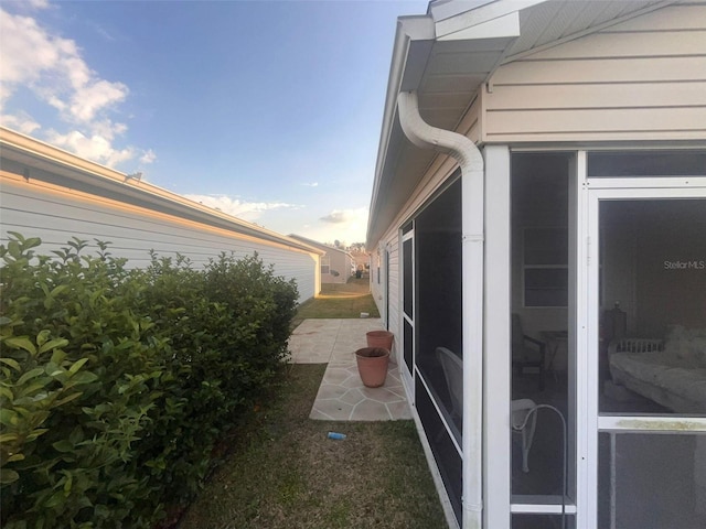 view of side of home with a sunroom and a patio