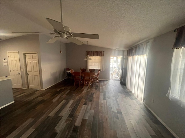 unfurnished dining area featuring ceiling fan, lofted ceiling, dark wood-type flooring, and a textured ceiling