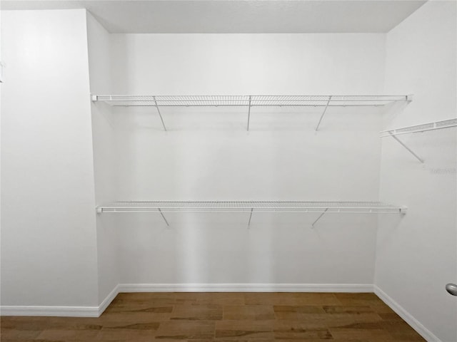 walk in closet with dark wood-type flooring