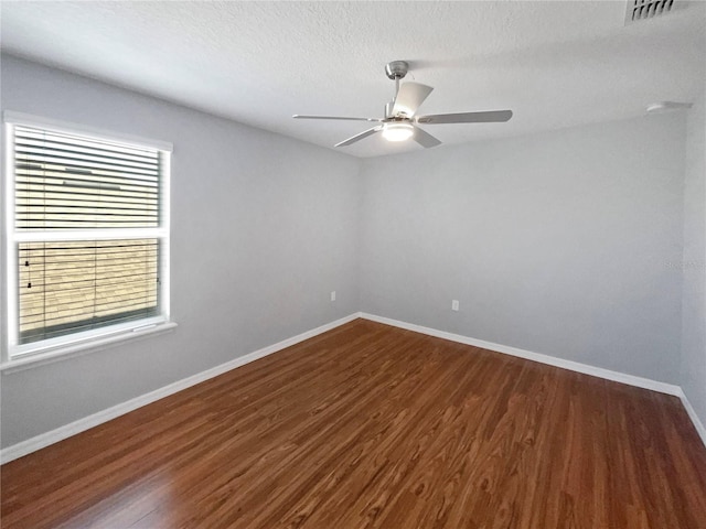 spare room with a textured ceiling, dark wood-type flooring, and ceiling fan