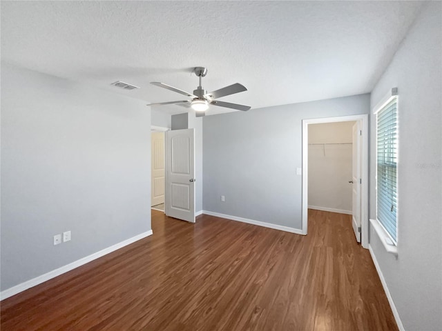 unfurnished room featuring ceiling fan, dark hardwood / wood-style floors, and a textured ceiling