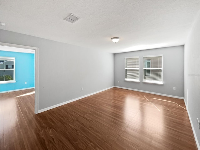 spare room with dark hardwood / wood-style floors and a textured ceiling