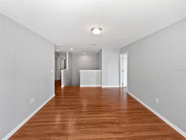 unfurnished room with hardwood / wood-style flooring and a textured ceiling